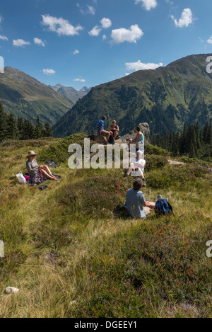 Un piccolo gruppo di escursionisti per adulti facendo una breve sosta per un pic-nic lungo il Madrisa a Klosters trail. Svizzera Foto Stock