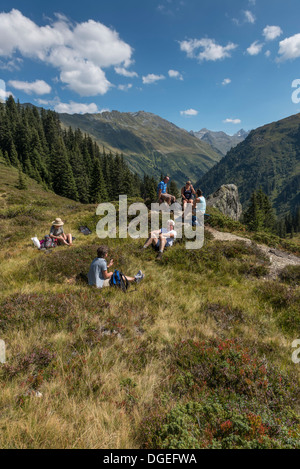 Un piccolo gruppo di escursionisti per adulti facendo una breve sosta per un pic-nic lungo il Madrisa a Klosters trail. Svizzera Foto Stock