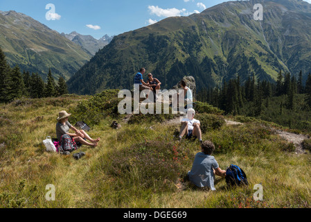 Un piccolo gruppo di escursionisti per adulti facendo una breve sosta per un pic-nic lungo il Madrisa a Klosters trail. Svizzera Foto Stock