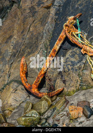 Old Rusty Anchor si trova abbandonato su Rocks sulla costa della Scozia Foto Stock