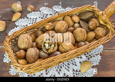 Un assortimento di dadi in un cestino sul tavolo di legno Foto Stock