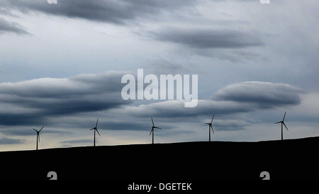 Cinque le turbine eoliche su una collina, cloud pesante dietro. Foto Stock