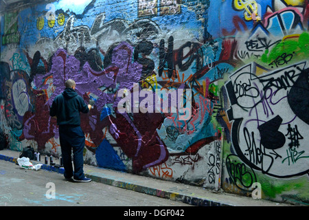 Lad dipinto graffiti sui muri della pubblica strada urbana tunnel Foto Stock