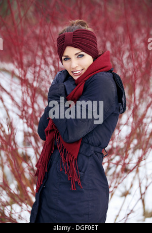 Shivering donna con sciarpa rossa in un freddo inverno park Foto Stock