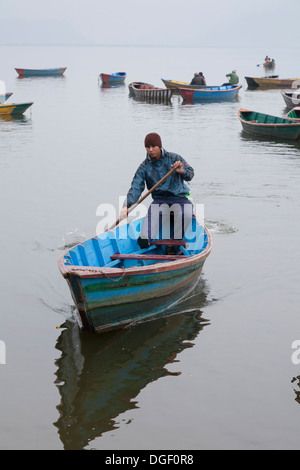 Giovane uomo paddling una barca sul Lago Phewa - Pokhara, valle di Pokhara, Gandaki Zona, Nepal Foto Stock