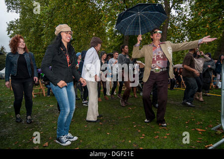 Russell Square, Bloomsbury, Londra, UK, 20 Ottobre 2013 - The Bloomsbury Festival 2013, un 'autunno festival di arte, di conoscenze e di Immaginazione' featured molti eventi eclettico per il pubblico di godere. Qui, un uomo in un costume colorato che impugnano un ombrello, conduce la danza, nella pioggia torrenziale, alla salsa cubana musica fornita dalla band di 'Sarabanda'. Credito: Stephen Chung/Alamy Live News Foto Stock