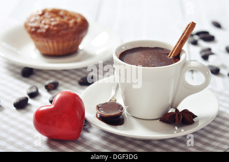Cioccolata in tazza con muffin e pietra rossa cuore su sfondo di legno Foto Stock