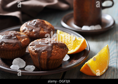 Muffin alla carota con il cioccolato fuso e arance fresche frutta su sfondo di legno Foto Stock