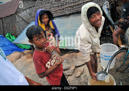 Bambini cambogiani sotto la pioggia al villaggio galleggiante sul lago Tonle Sap vicino a Siem Reap, Cambogia. Foto Stock