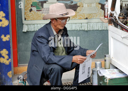 Uomo che legge il giornale, Barkhor, Lhasa, in Tibet, in Cina Asia Foto Stock