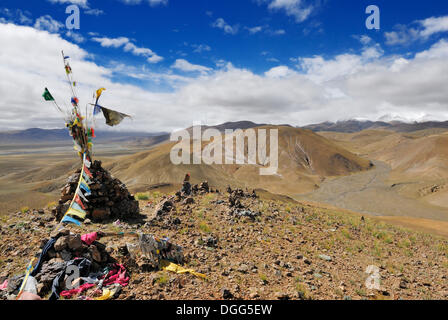 Il tumulo di pietra con la preghiera le bandiere, Tingri altopiano coperto di neve e cime di montagna sotto nuvole basse sul retro, Himalaya, Tibet, Cina Foto Stock