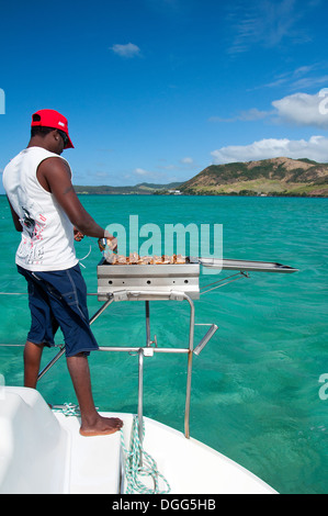 MAURITIUS - 25 giugno: membro di equipaggio preparare il cibo per i turisti in viaggio in catamarano il 25 giugno 2013, a Maurizio. Foto Stock