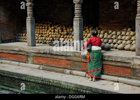 Le donne in abito tradizionale in piedi nella parte anteriore di una pila di ceramiche, Bhaktapur, Valle di Kathmandu, Nepal, Asia Foto Stock