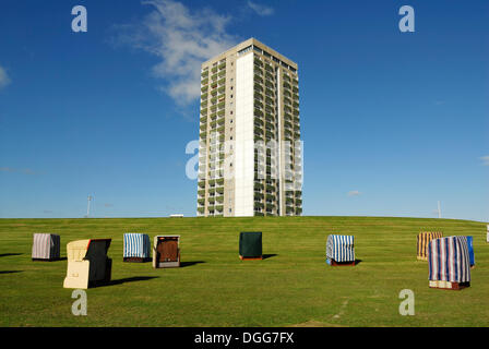 Coperto e sedie da spiaggia in vimini in piedi sul prato di fronte un grattacielo, Buesum, distretto di Dithmarschen, Schleswig-Holstein Foto Stock