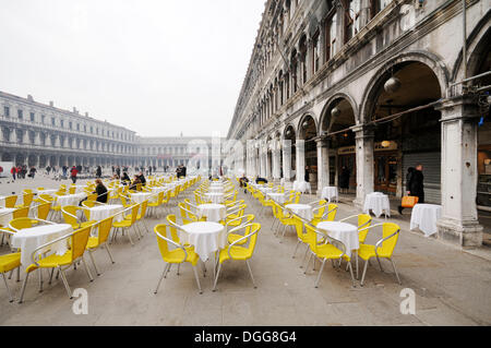 Le sedie e i tavoli di un caffè all'aperto in Piazza San Marco, Procuratie edifici, quartiere San Marco, Venezia, Venezia, Veneto Foto Stock