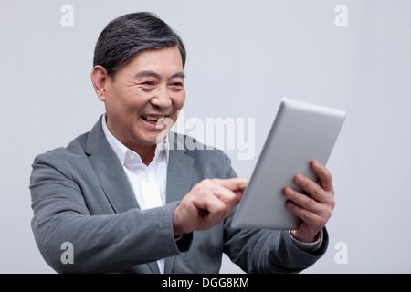 Un vecchio uomo tenendo un tablet Foto Stock