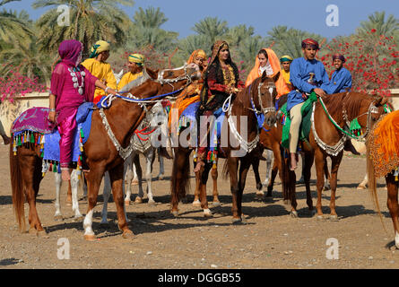 Omani gli uomini e le donne in abito tradizionale seduta su un cavallo, Nakhl, Nakhal, Batinah regione, il sultanato di Oman, Arabia Foto Stock