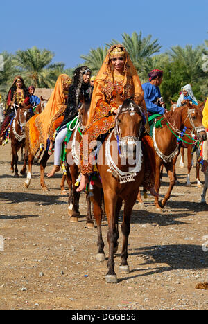 Omani gli uomini e le donne in abito tradizionale seduta su un cavallo, Nakhl, Nakhal, Batinah regione, il sultanato di Oman, Arabia Foto Stock