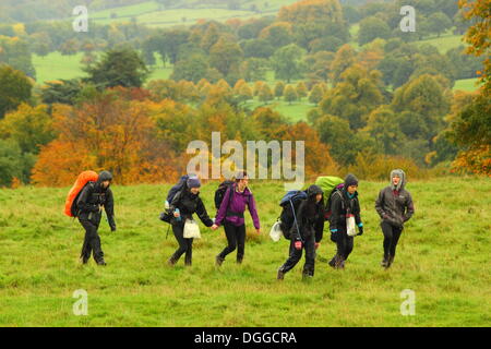 Gli escursionisti brave pioggia come si incrociano autunnale di parco che circonda la Chatsworth House, il Peak District, England, Regno Unito Foto Stock