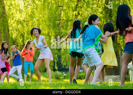 Donna e un gruppo di ragazze facendo rimorchiatore di guerra nel parco Foto Stock