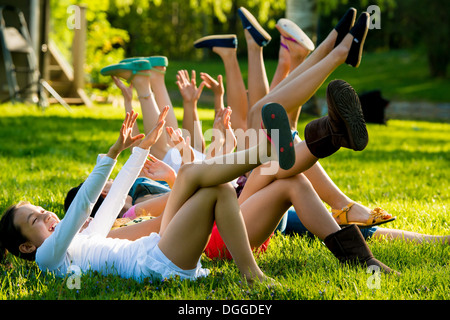 Le ragazze che giace sull'erba con le braccia e le gambe sollevate Foto Stock