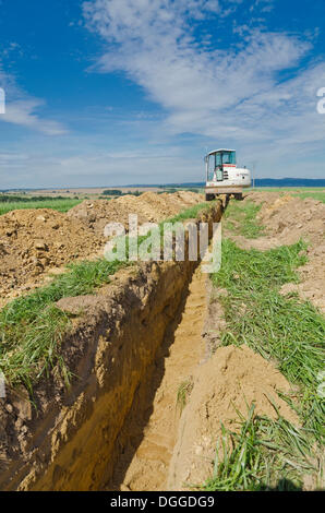 Escavatore a scavare un canale attraverso il paesaggio agricolo, Laurich, Sassonia Foto Stock