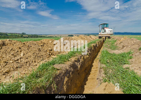 Escavatore a scavare una fossa attraverso l'agricoltura paesaggio, Laurich, Sassonia Foto Stock