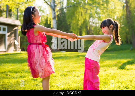 Due ragazze tenendo le mani in giardino Foto Stock