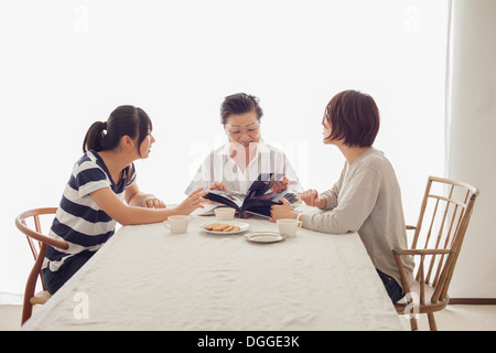 Tre generazioni la famiglia guardando album di foto Foto Stock