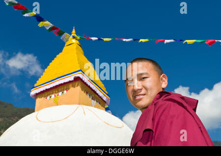 Ritratto di un giovane monaco tibetean, stupa bianchi con prayerflags nel retro, Bhandar, Solukhumbu quartiere Zona Sagarmāthā Foto Stock