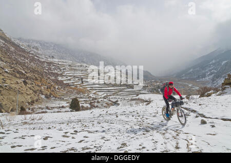 Ciclista in sella alla sua moto nella neve fino verso Thorong La Pass (5416 m), Manang, Regione di Annapurna, Nepal Foto Stock