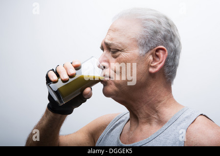 Senior uomo frullato di bere dal bicchiere Foto Stock
