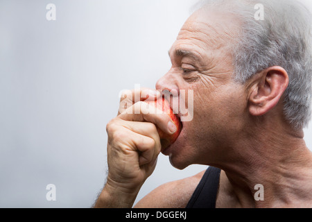 Senior uomo mangiare apple, close up Foto Stock