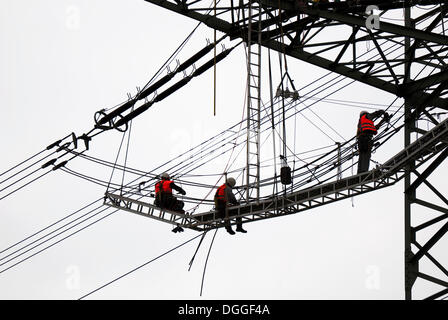 Il sovraccarico di lavoro linemen su un pilone Foto Stock