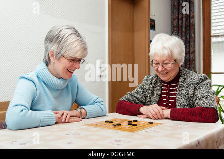 Due donne anziane, cittadini anziani, madre e figlia, giocando il gioco di bordo "nove uomini Morris', Rehna Foto Stock