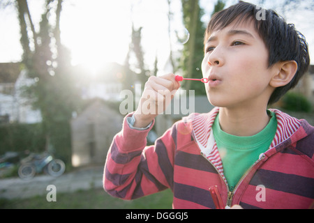 Ragazzo soffiare bolle con bacchetta, close up Foto Stock