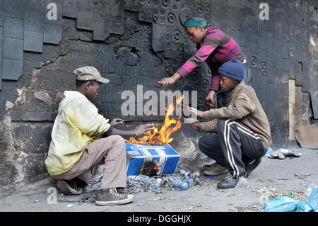 I bambini di strada di riscaldamento attorno a sé un incendio nelle prime ore del mattino, Hillbrow district, Johannesburg, Sud Africa e Africa Foto Stock