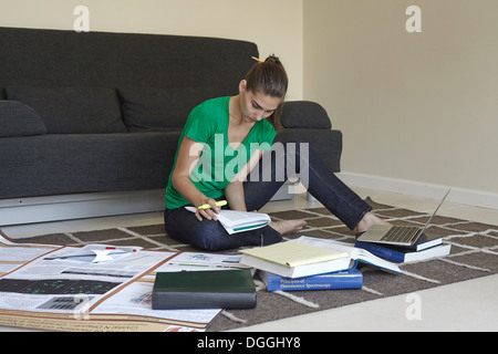 Metà donna adulta seduta sul pavimento a studiare Foto Stock