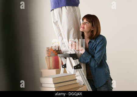 Donna che mantiene sull uomo sulla scala Foto Stock