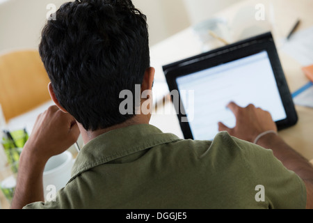 Maschio di lavoratore di ufficio tramite il display tattile sulla tavoletta digitale Foto Stock