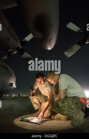 Il personale Sgt. Kyle diritto personale e Sgt. Joshua Jorgensen, 774th Airlift Expeditionary Squadron equipaggio capi, consultare un tecnico per risolvere i problemi di un C-130H Hercules problema del motore in corrispondenza di Bagram Airfield, Parwan Provincia, Afghanistan, 6 ott. 2013. Hercules airc Foto Stock