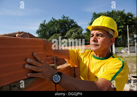 Uomo con un elmetto lavorando su un sito di costruzione della 'Esperanca' alloggiamento co-operativa, ogni famiglia di aiutare con il progetto Foto Stock