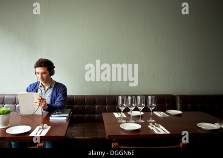 Giovane uomo che indossa le cuffie in ristorante Foto Stock