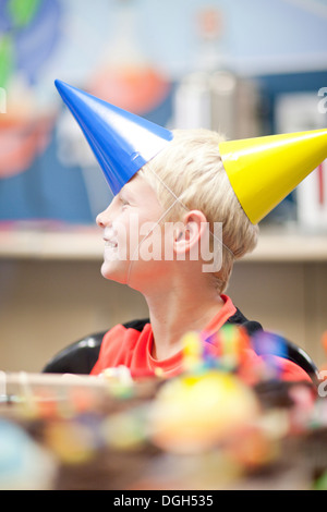 Ragazzo alla festa di compleanno di indossare due cappelli di partito Foto Stock