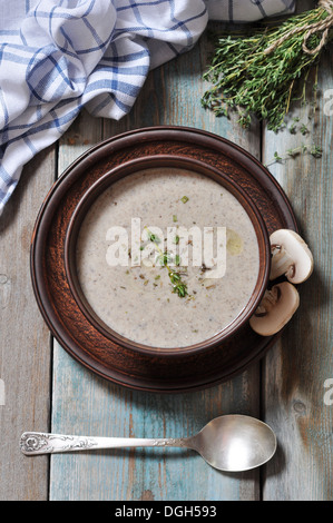 Crema di funghi zuppa con erbe aromatiche in vaso marrone su sfondo di legno Foto Stock