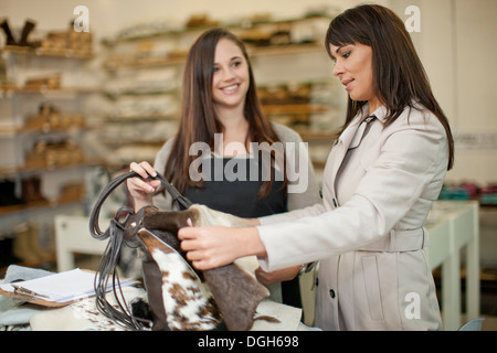 Il cliente e il negozio assistant guardando alla borsa in pelle Foto Stock