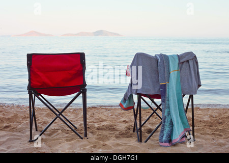 Due volte su sedie a sdraio su di una spiaggia di sabbia al tramonto Foto Stock