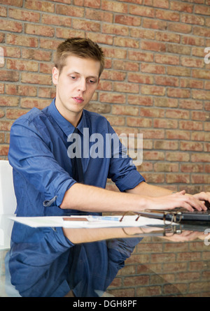 Giovane imprenditore seduta a tavola e lavorare con i grafici Foto Stock