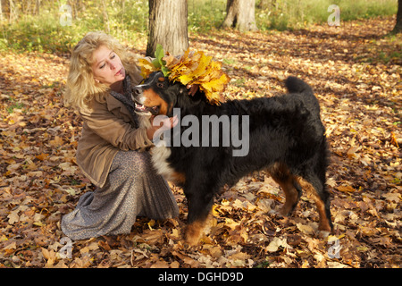 Donna mette corona da foglie di giallo sul suo cane Foto Stock