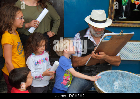 Parigi Francia,18° arrondissement,Montmarre,Place du Tertre,uomo uomo maschio,disegnatore,disegno,ragazzo ragazzi ragazza maschio,ragazze femmina bambini,curioso,Fr Foto Stock